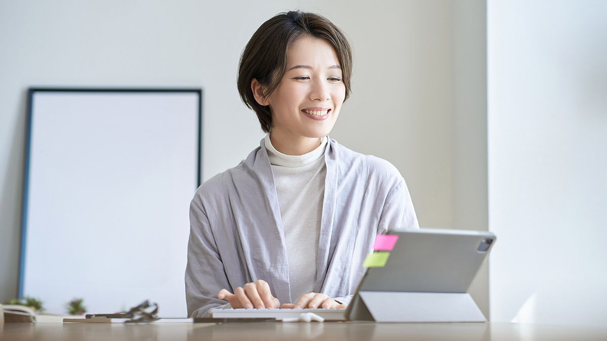 笑顔でタブレットのキーボードを打つ女性